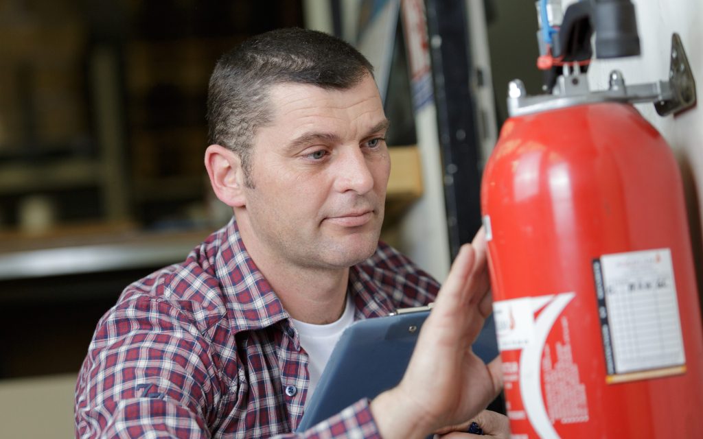 Man inspecting a fire extinguisher as part of his fire safety checks