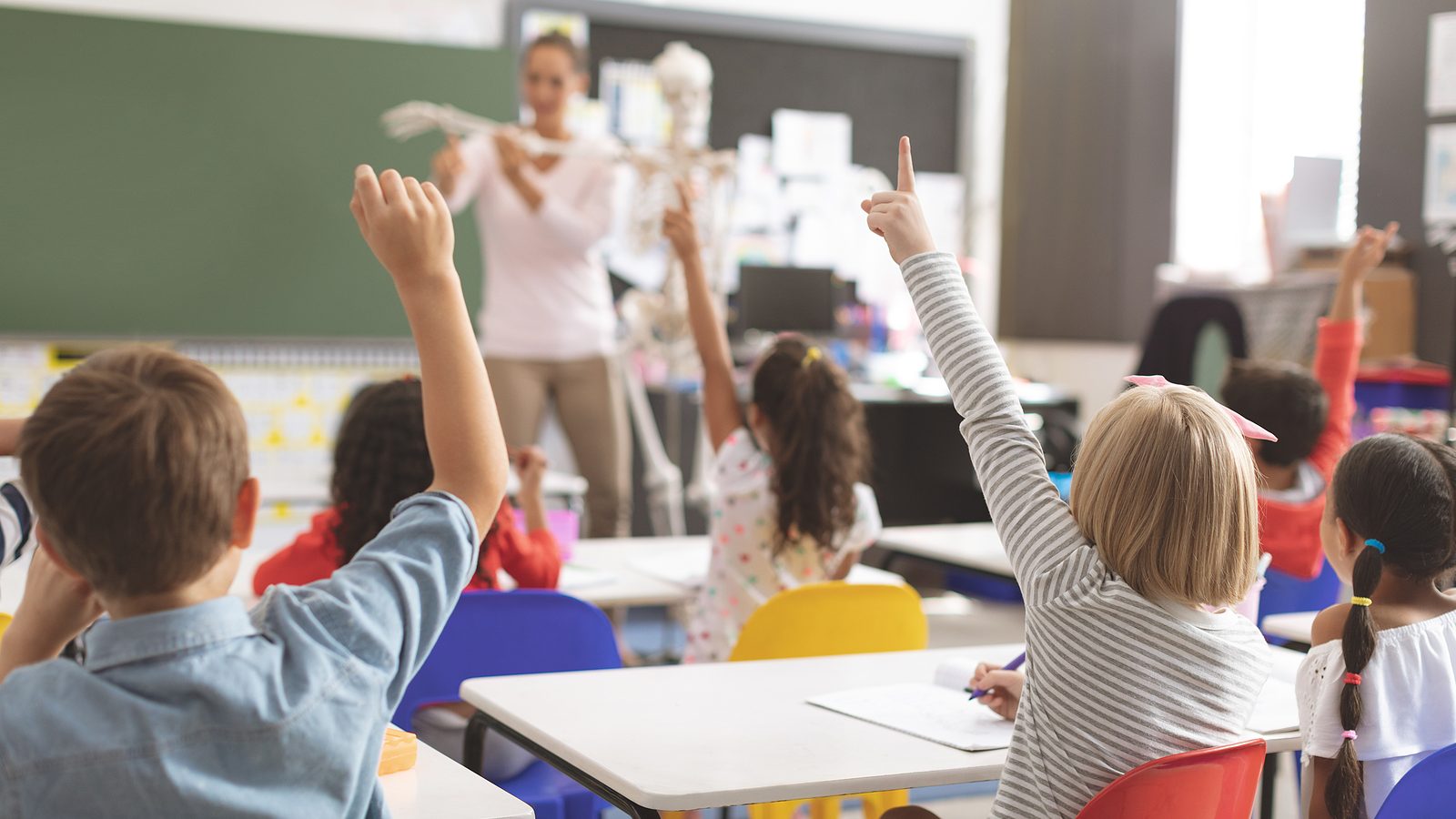 Full Classroom with everyone raising their hands