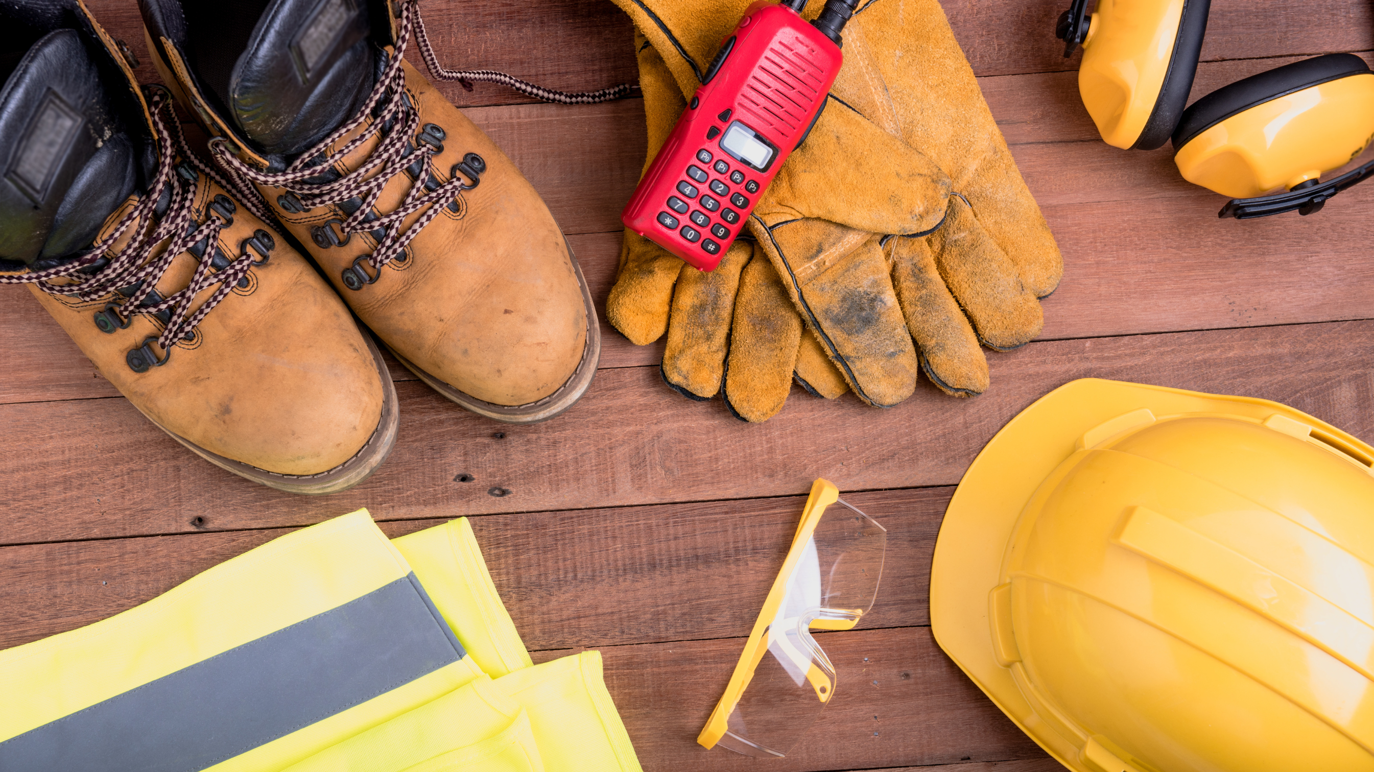 A variety of PPE displayed out on a table, showing protective boots, gloves, ear protection, safety glasses, a hard hat and a high-vis jacket.